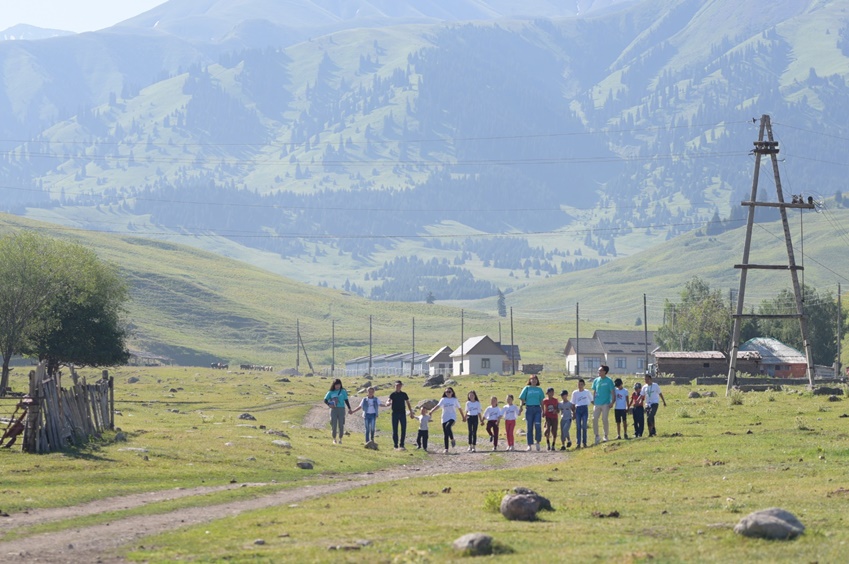 참가자들과 아이들이 손을 잡고 학교로 향하고 있다.