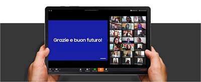 의문의 손이 비대면 수업 또는 회의가 진행되는 태블릿을 들고 있다. 태블릿 내 공유된 화면에는 다음과 같이 적혀있다.  "Grazie e buon futuro!"