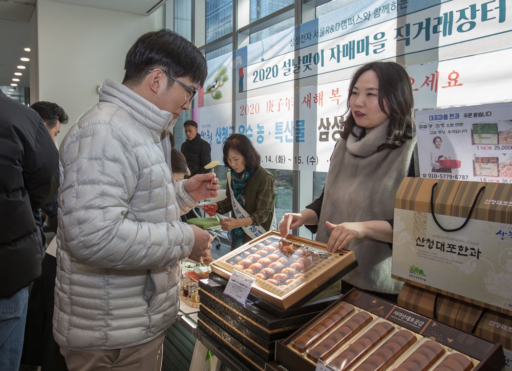 삼성 서울R&D캠페스에서 설을 앞두고 열린 직거래 장터에서 삼성전자 임직원들이 자매마을과 중소기업이 생산한 농축수산물을 구매하고 있다.