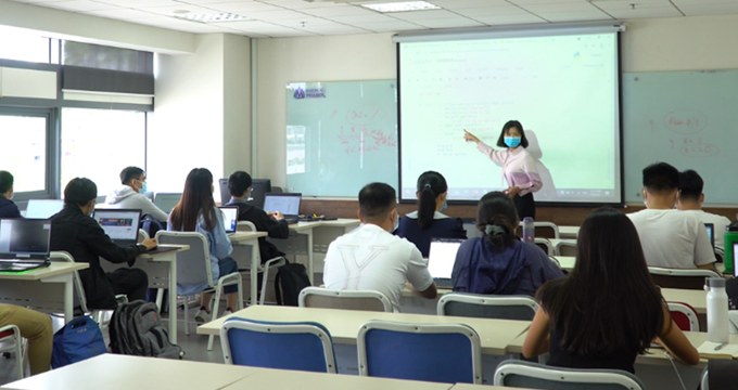 A teacher conducting a lesson in front of a projector screen