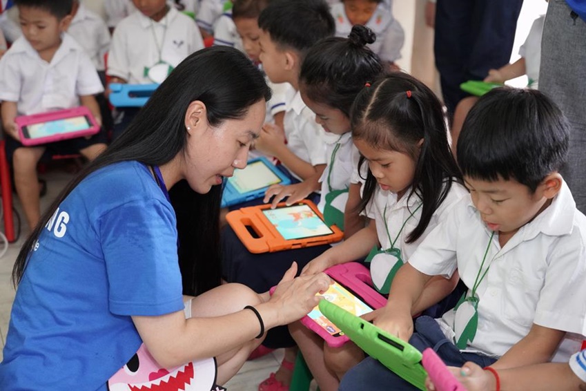 임직원 봉사자가 태블릿을 활용해 캄보디아 유치원 학생들을 지도하고 있다.